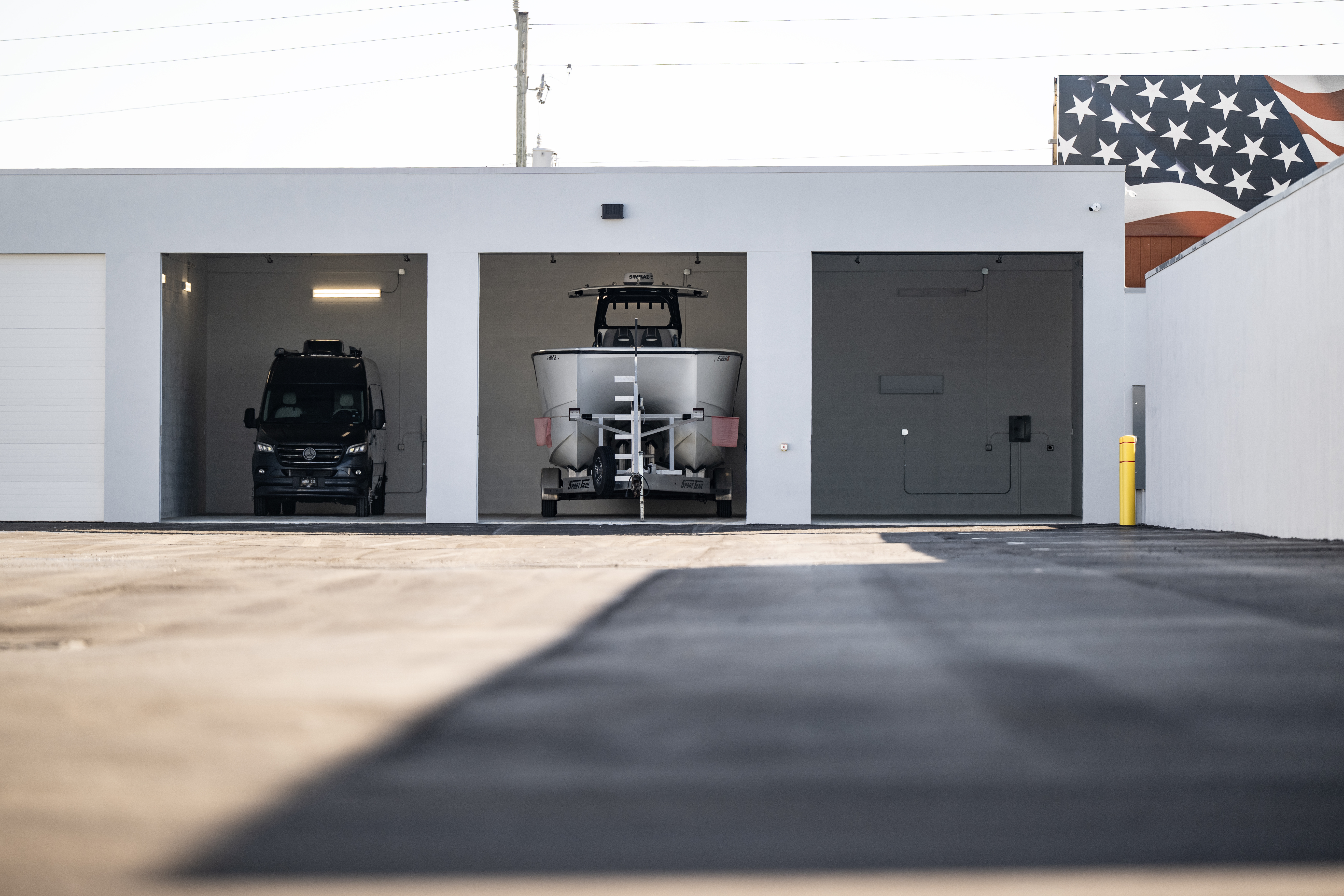 Row of large private climate-controlled storage units at MetroMaxx showing a luxury van and boat stored indoors with wide concrete drive aisles in Fort Myers, Florida